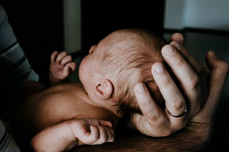 baby laying in father's arms