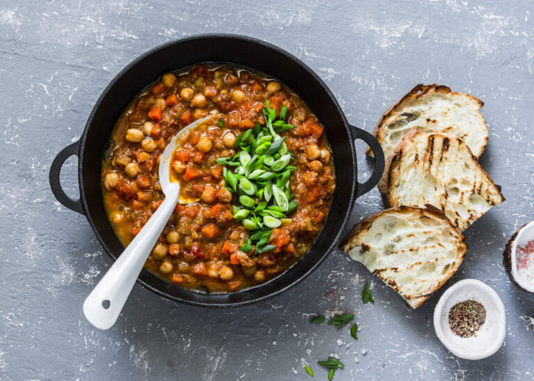 Moroccan-inspired chickpea stew in a black pot with a side of freshly sliced bread