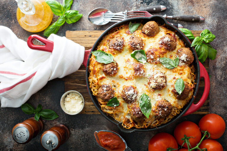 Cheesy spaghetti and meatball pie in a red skillet