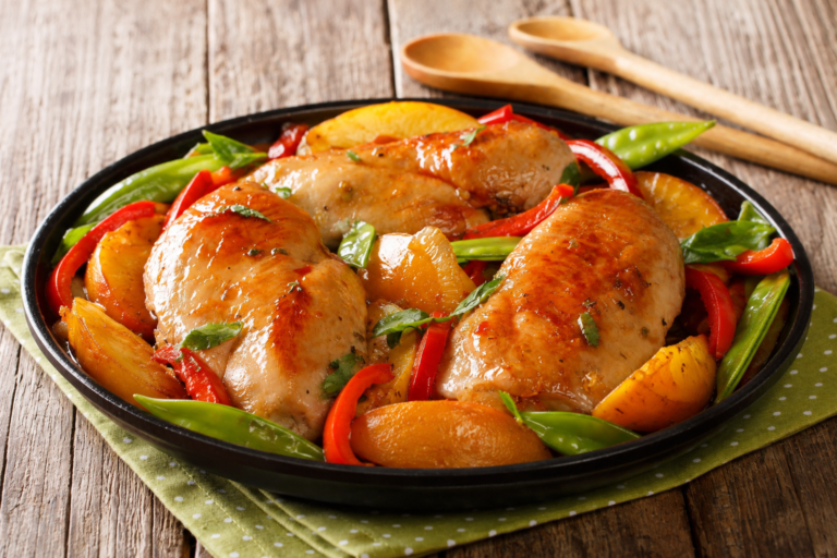 Summer peach and chicken skillet in a black pan with utensils in the background