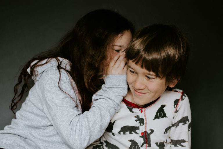 girl whispering in boy's ear