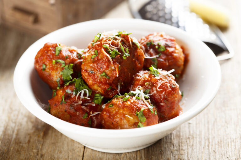 A pile of saucy meatballs in a white bowl