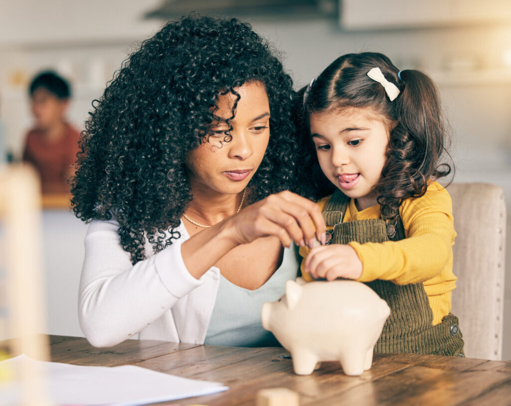 Mom and child putting money in a piggy bank, encouraging self-discipline in children