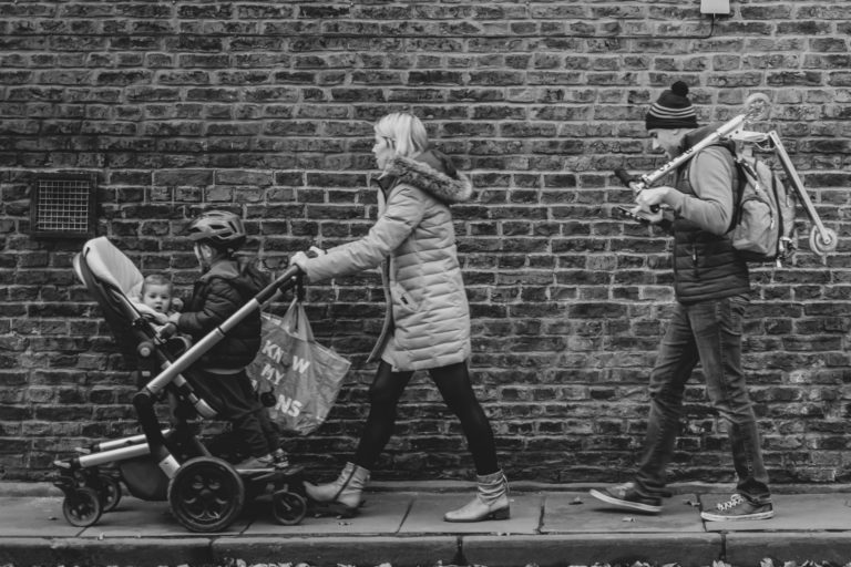 family walking down a street, dad trailing behind