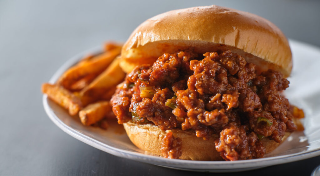 Vegan sloppy joes served with French fries on a white plate