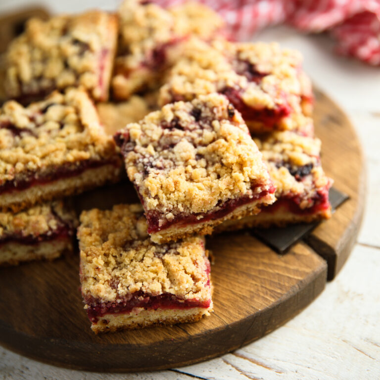 Cranberry-crumble oat squares on a round wooden cutting board