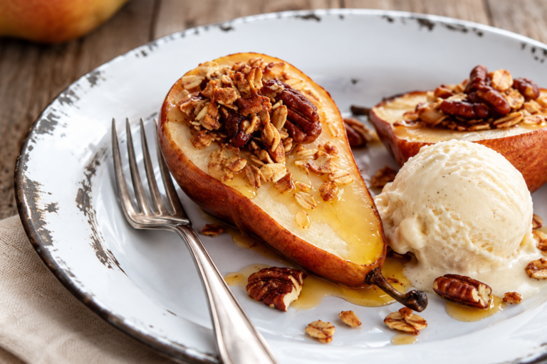 Maple-roasted pears with granola, served on a white plate with a scoop of vanilla ice cream