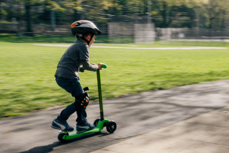 little boy on a scooter in summer