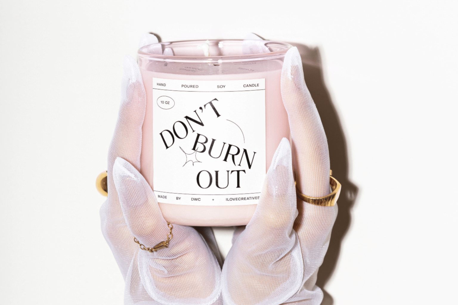 gloved hands holding a candle that says "don't burn out"