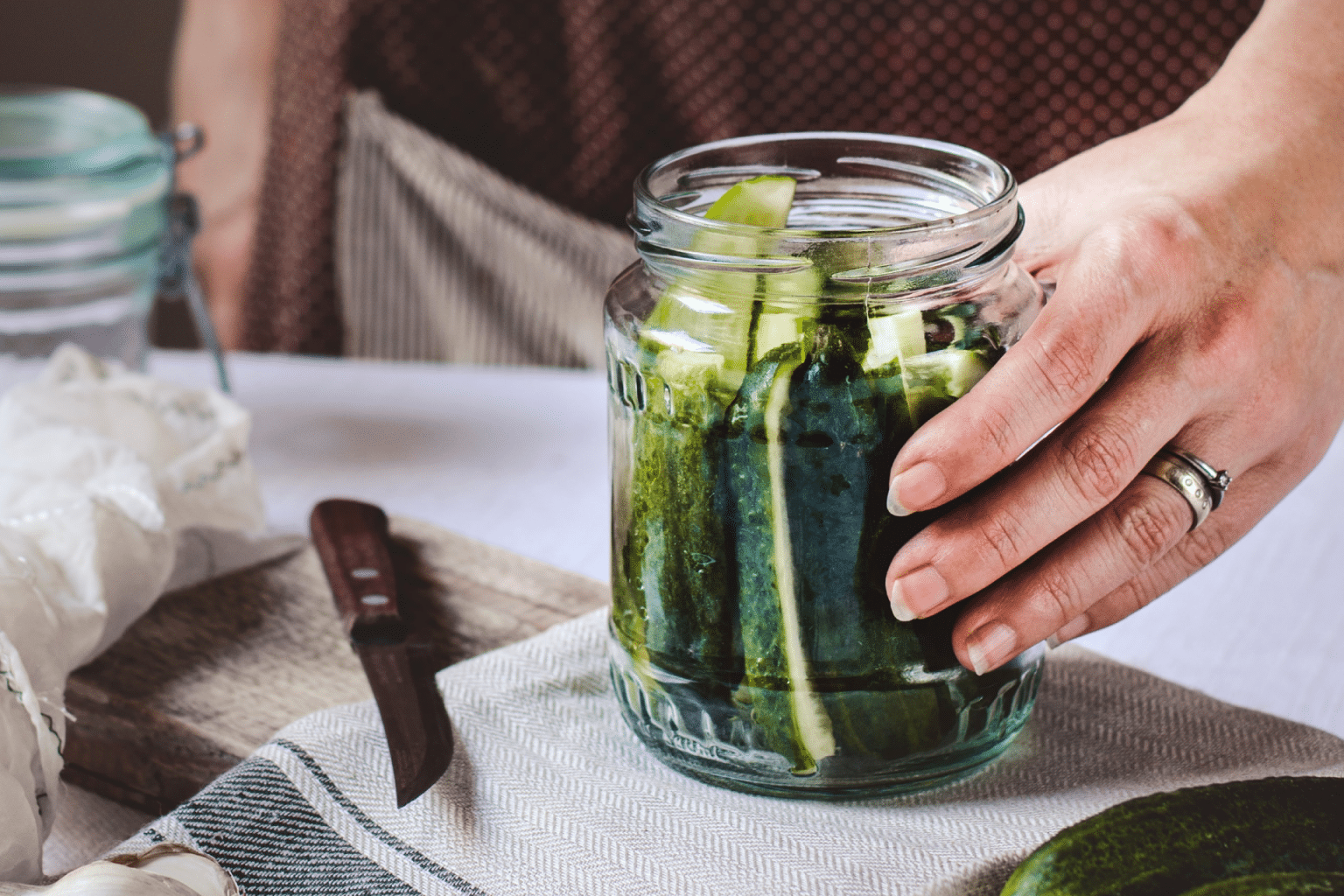 hand on a mason jar filled with quick fridge pickles