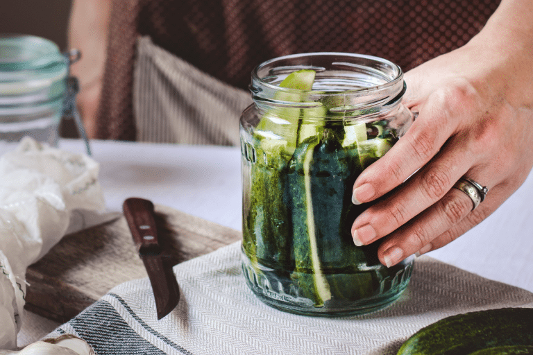 hand on a mason jar filled with quick fridge pickles