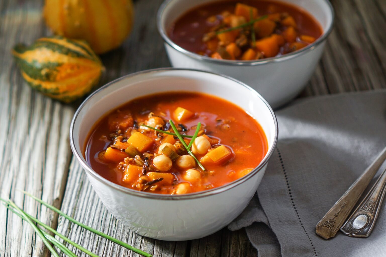 Bowl of veggie chili with butternut squash in the background