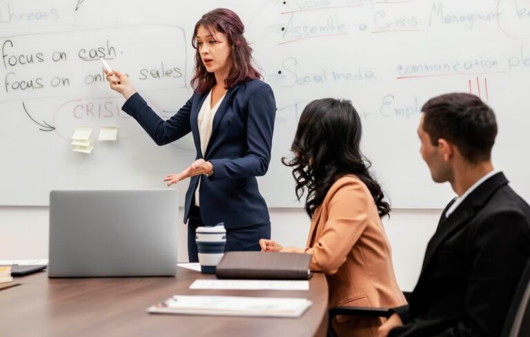 a woman pointing at a whiteboard