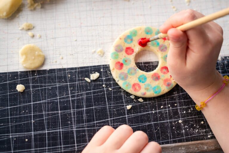 Hand decorating painted sugar cookies on an etched mat