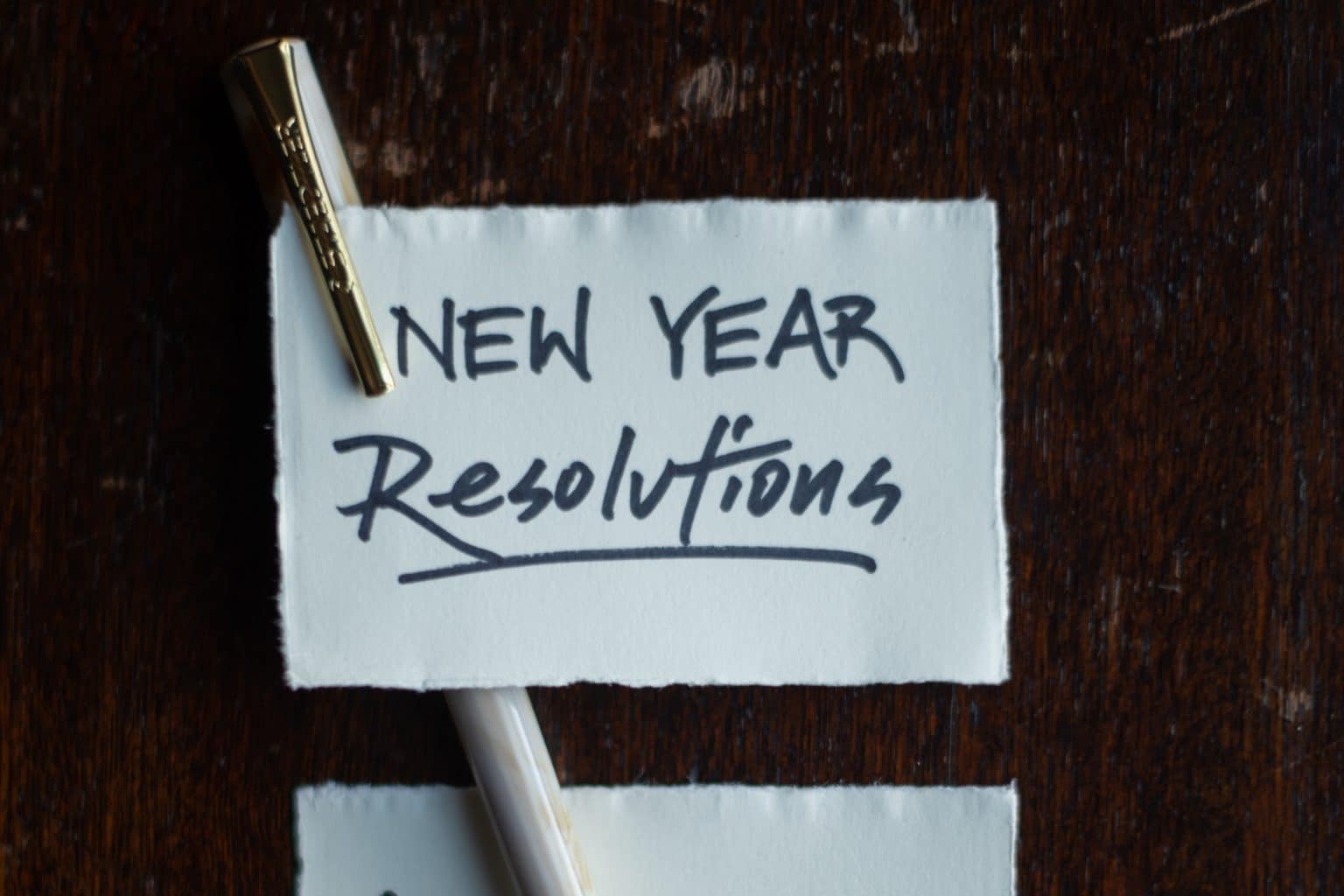 piece of paper with a pen that says "New Year Resolutions"