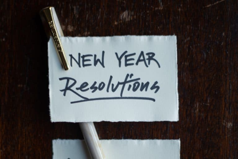 piece of paper with a pen that says "New Year Resolutions"