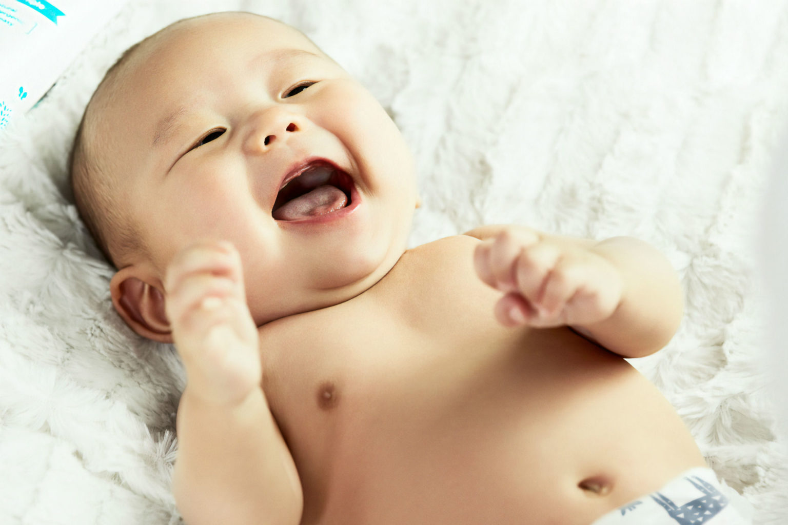 baby laying on bed smiling