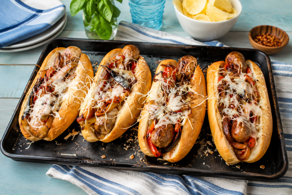 Sausage hoagies on a black baking dish, sitting on a striped tea towel