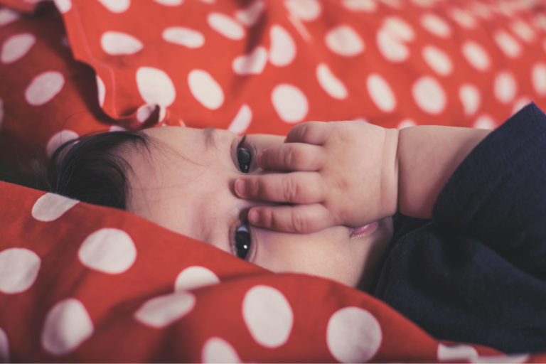 child laying in bed sucking his thumb