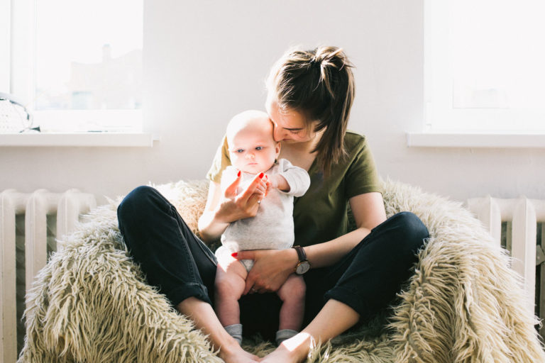 mother holding her baby on a sheepskin-covered chair