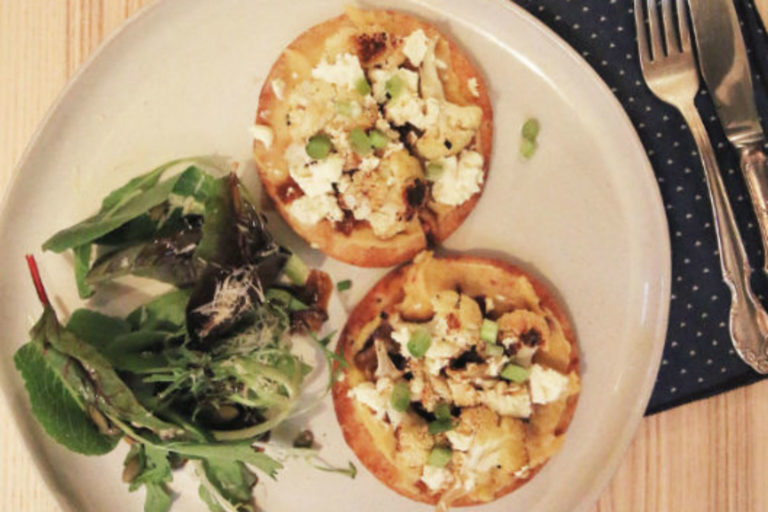 two mini flatbread pizzas with hummus and roasted cauliflower on top