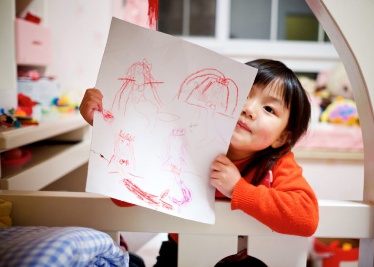 little girl holds up art