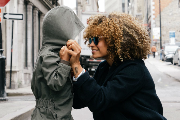 mom bending at child's level holding his hands