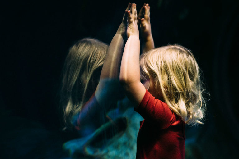 little girl pressing face against the glass of an aquarium