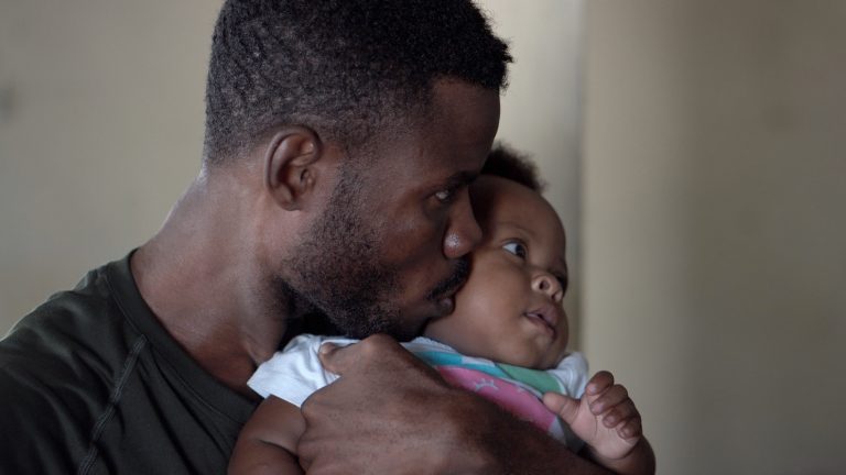 man holding a baby and kissing them on cheek