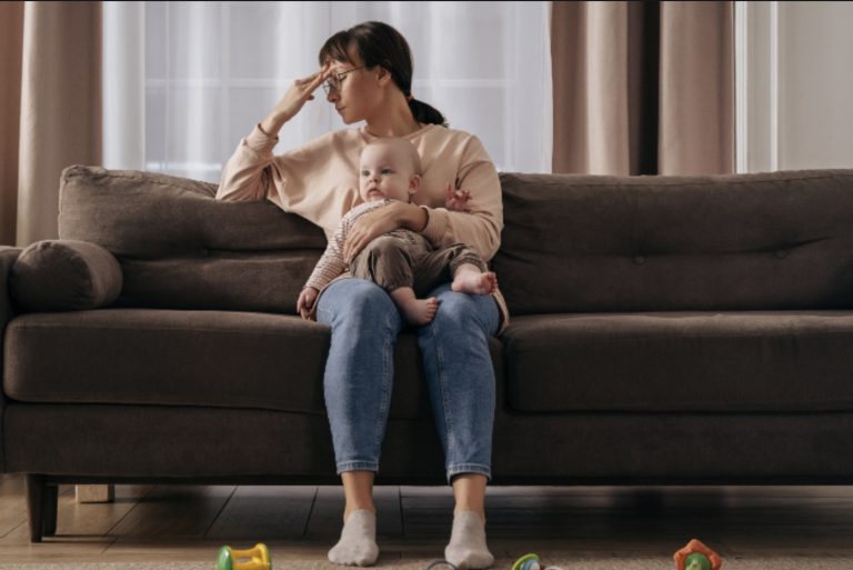 harried-looking mother holding baby on mat leave