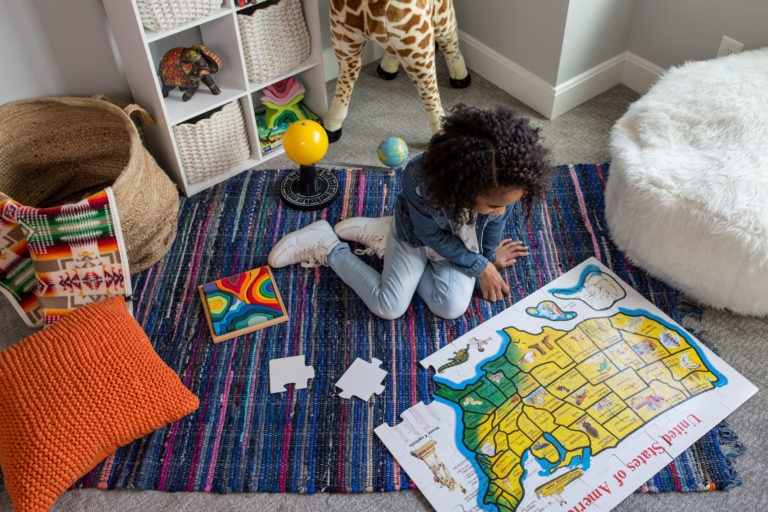 little girl playing with toys on bedroom floor