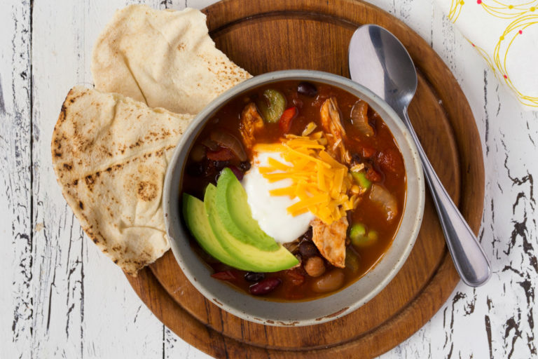 Slow cooker chicken chili topped with avocado, sour cream and cheese