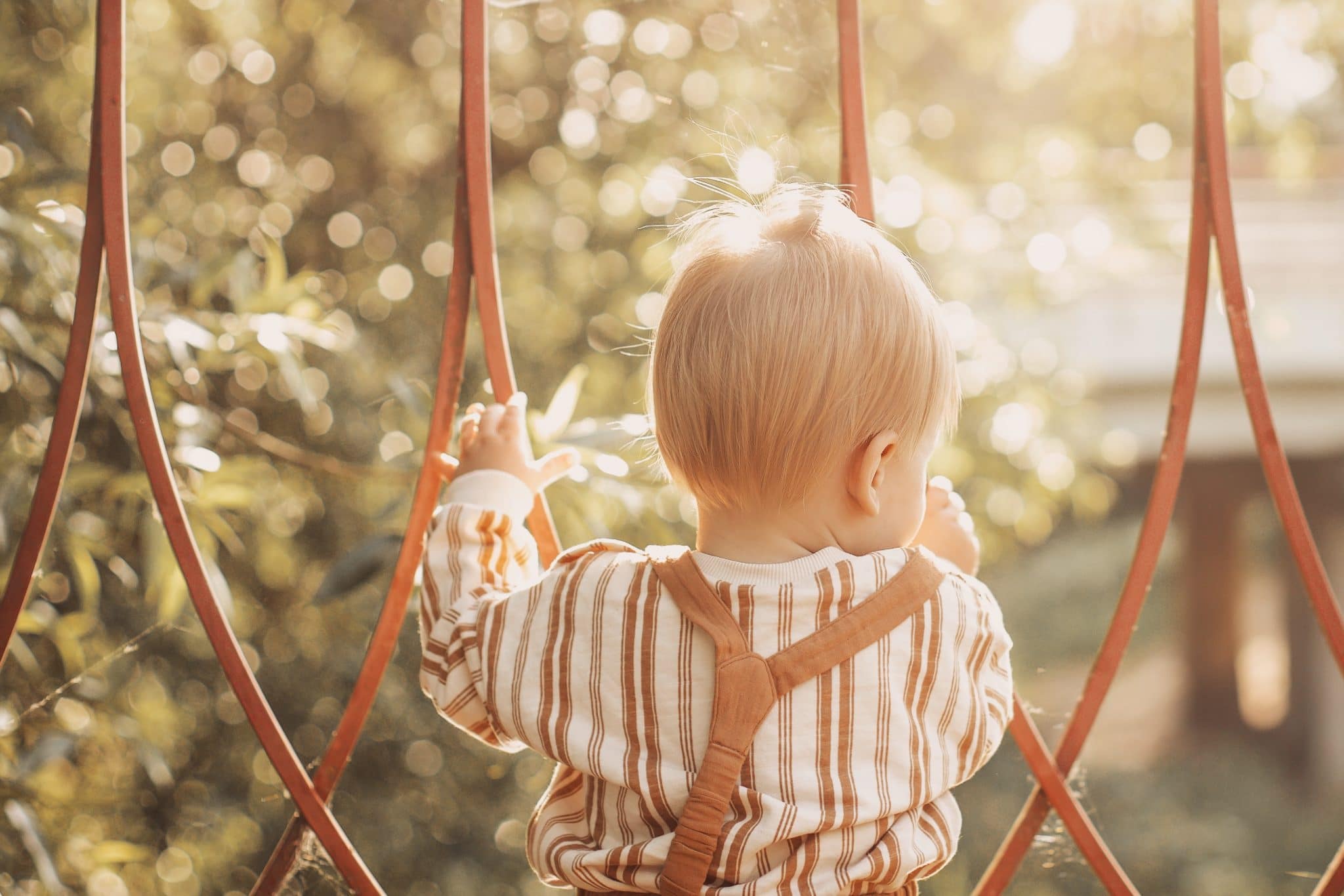 little boy playing on bars at a playground