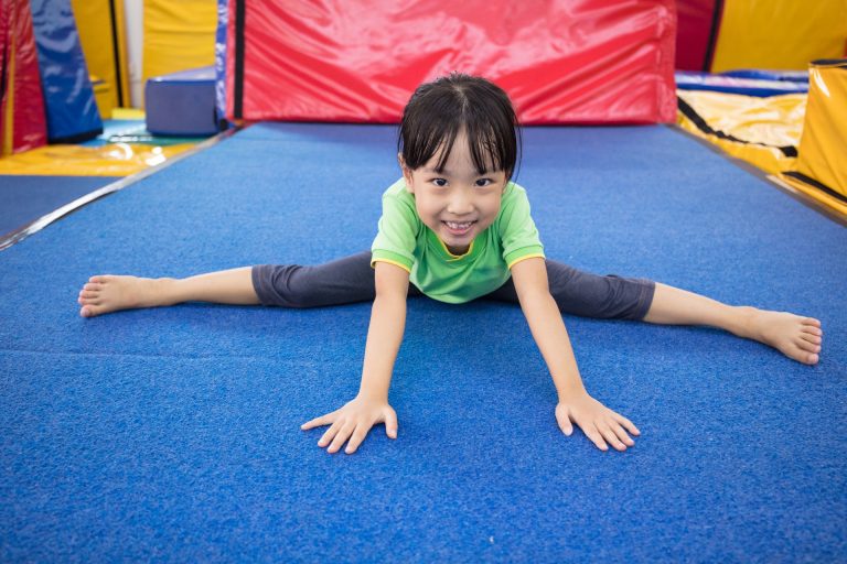 girl on a gym mat doing the splits