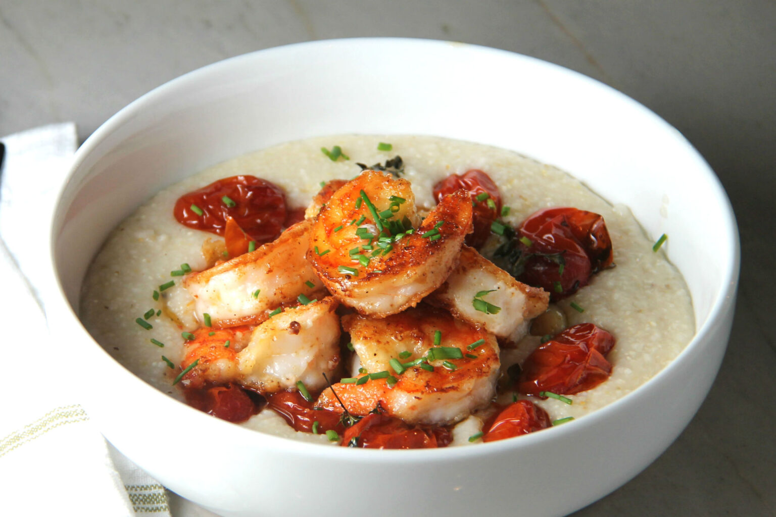 White bowl of shrimp and grits with roasted tomatoes