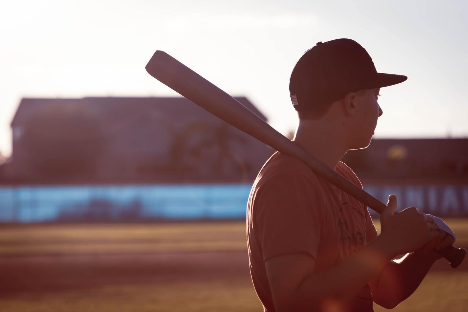 Boy with baseball bat on shoulder looking into the distance