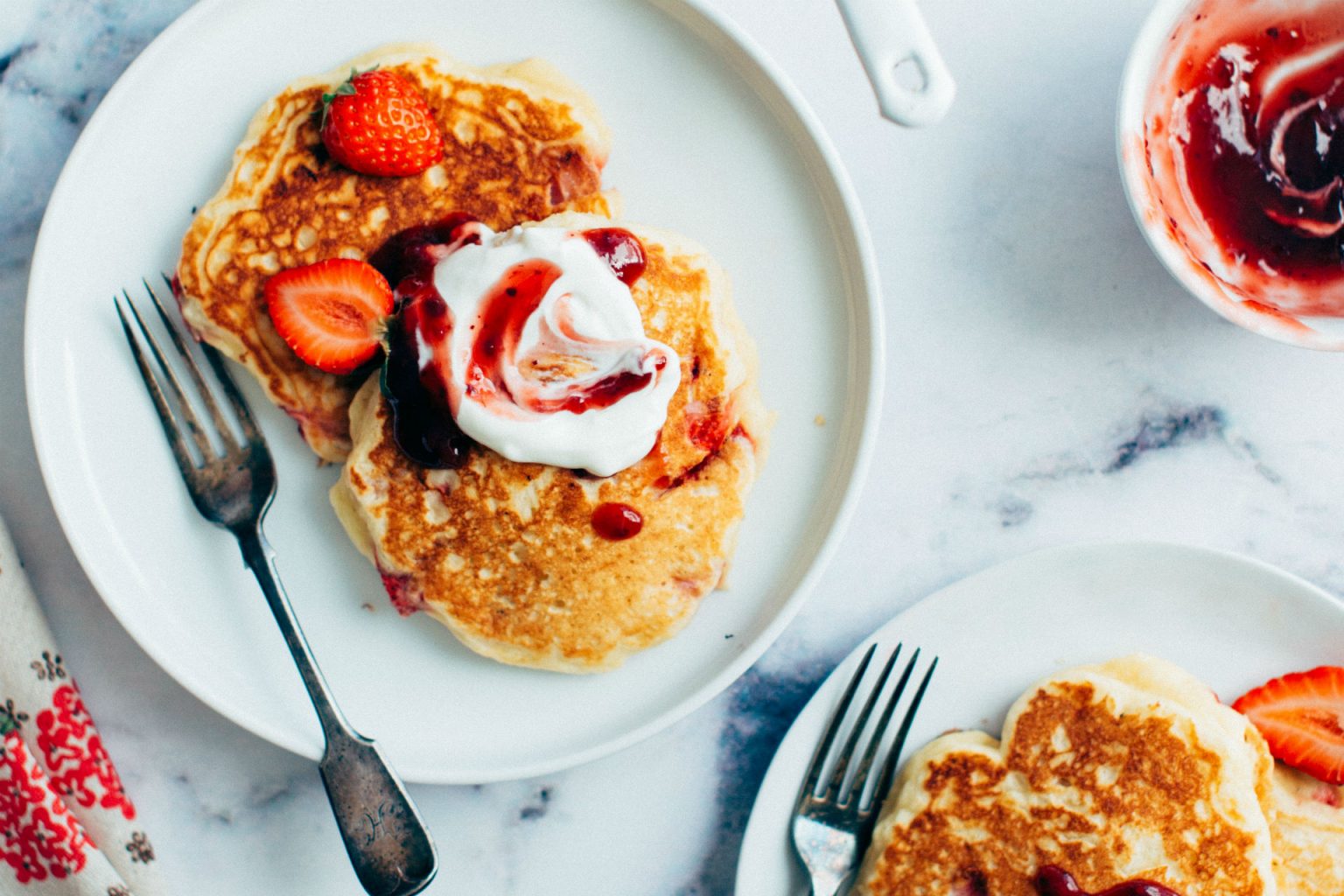 plate of pancakes with whipped cream and berries