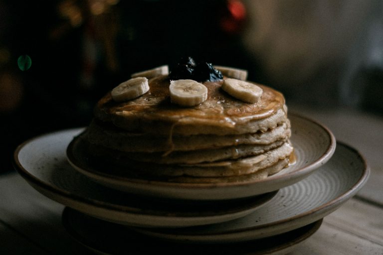 stack of pancakes topped with fruit and syrup