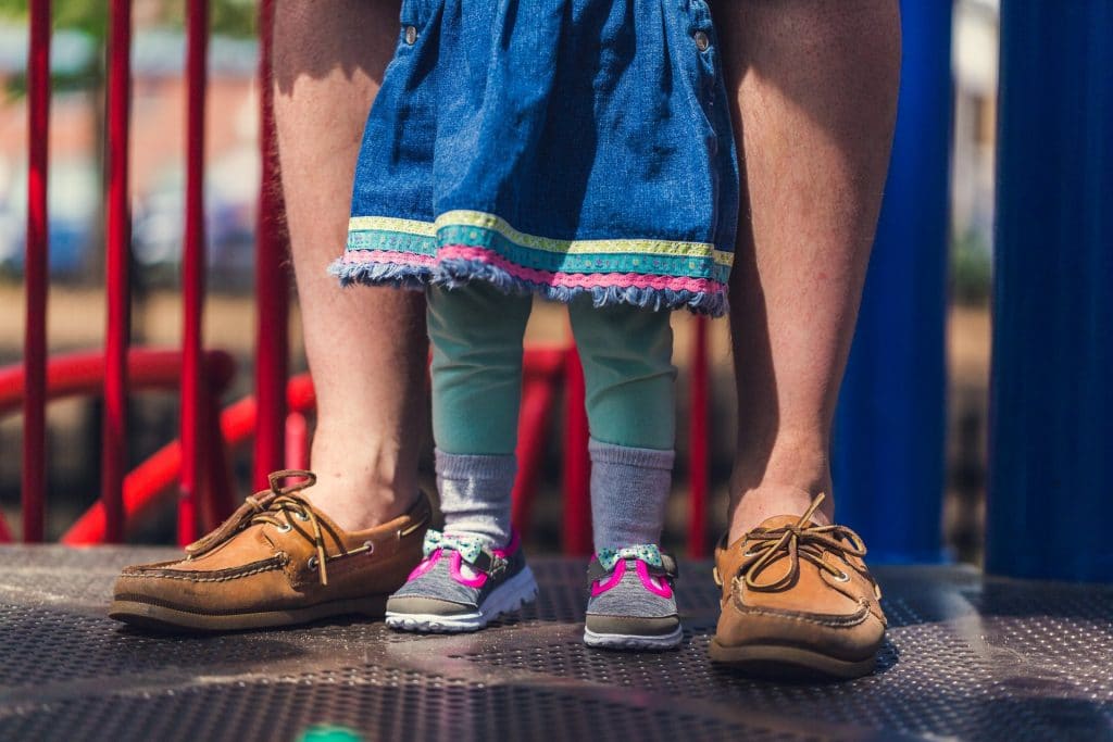 Child's feed inside her father's feet