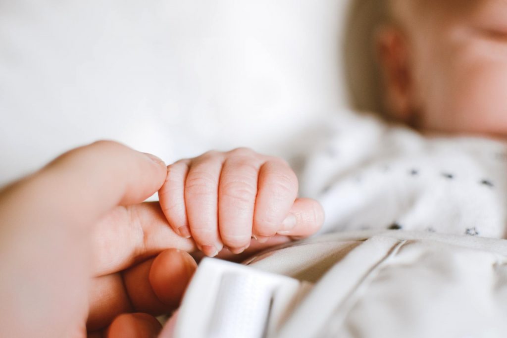 Parent holding hand of sleeping baby