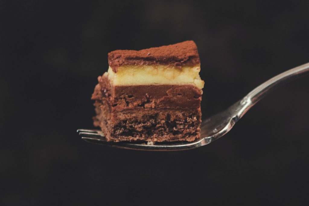 Classic Nanaimo bar on a fork, with a black background