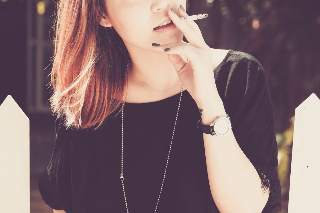 Red-haired woman in a black shirt smoking