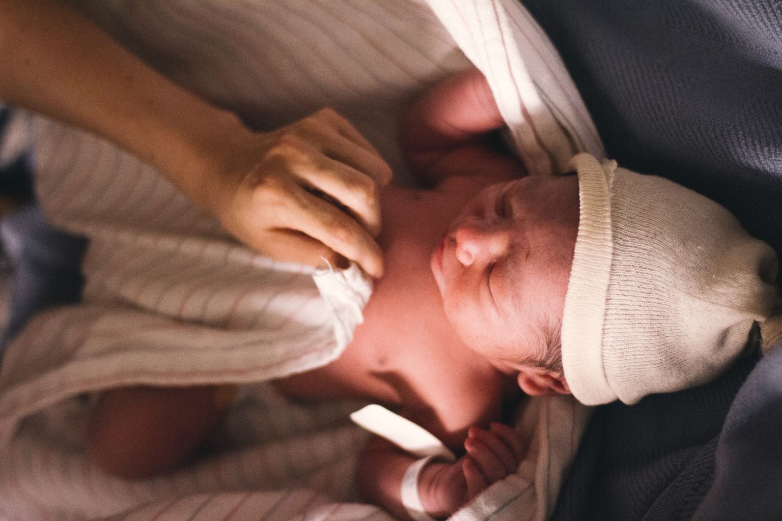 Newborn in hat being swaddled