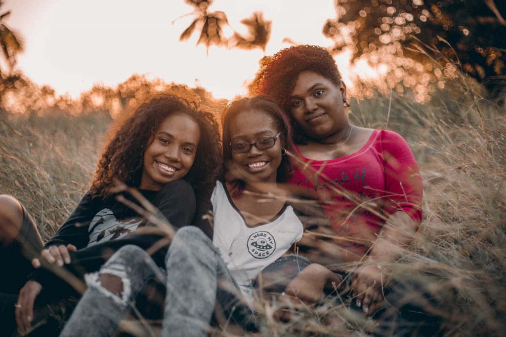 Two teenage girls sitting with female parent