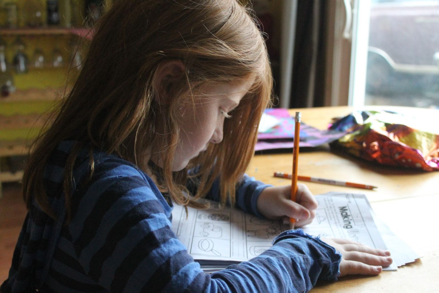 School-age girl completing a worksheet at a table