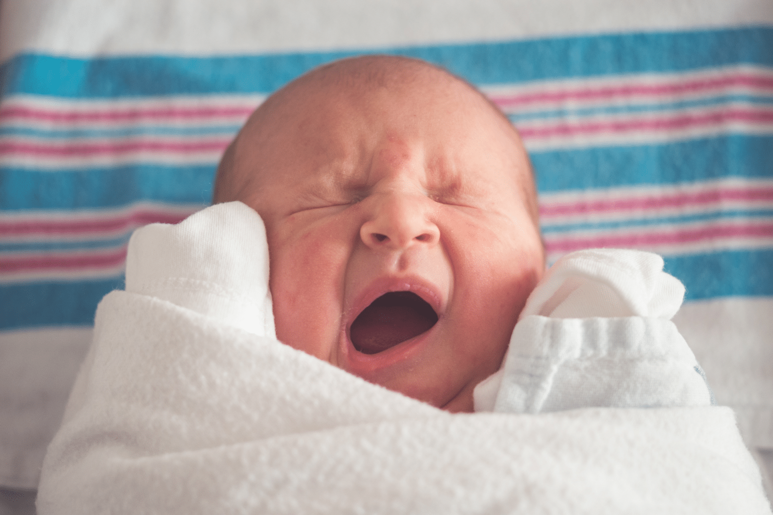 baby wrapped in iconic hospital blanket, baby is crying