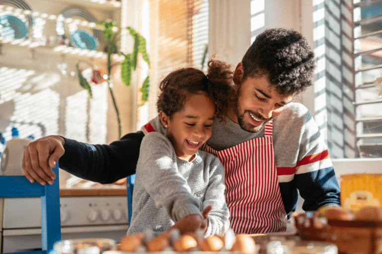 father and daughter look happy as they bake together