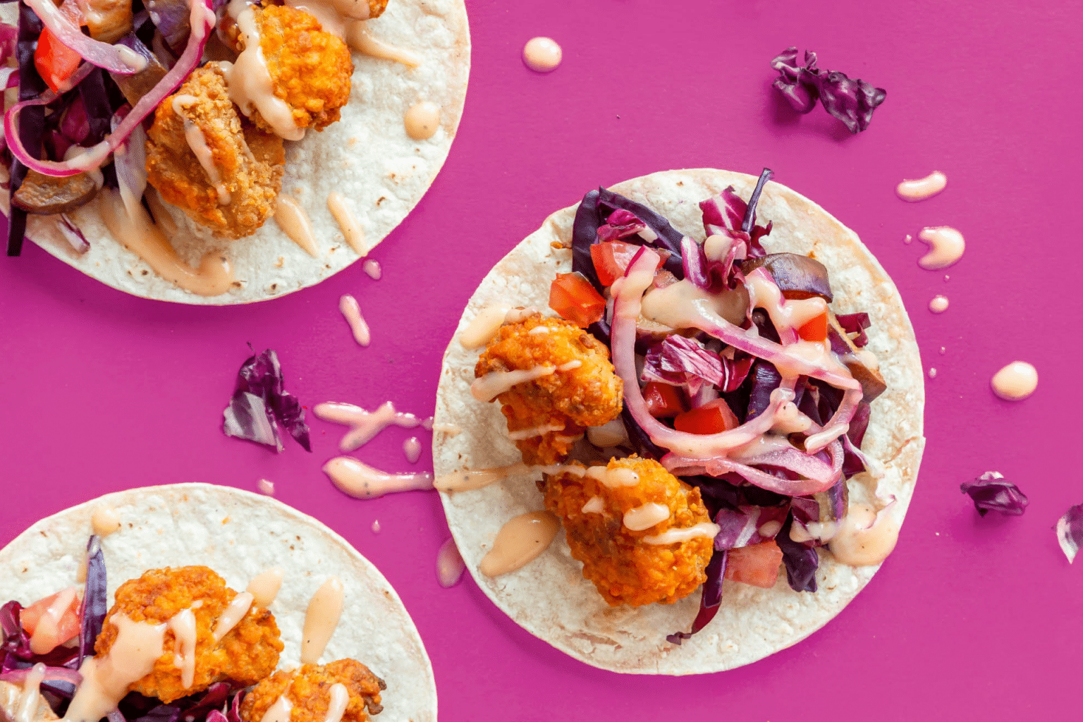 buffalo cauliflower tacos on a pink background