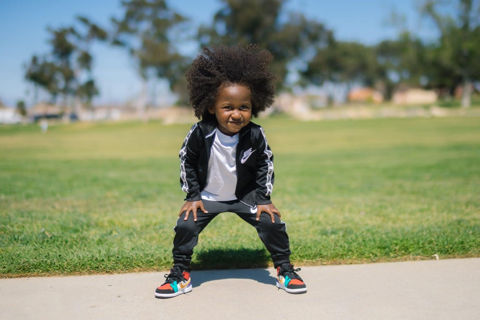 little boy in a track suit standing outside