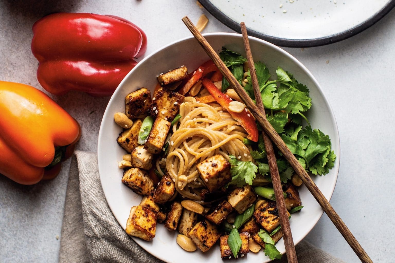 bowl of tofu and noodles with veggies and chopsticks